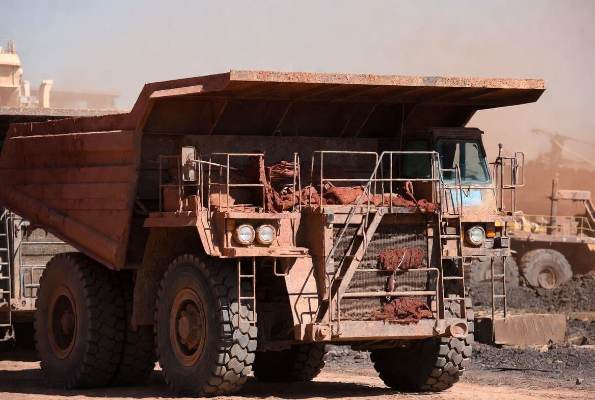 Heavy mining haul truck covered in thick dust and dirt due to lack of industrial cleaning at a South African mine